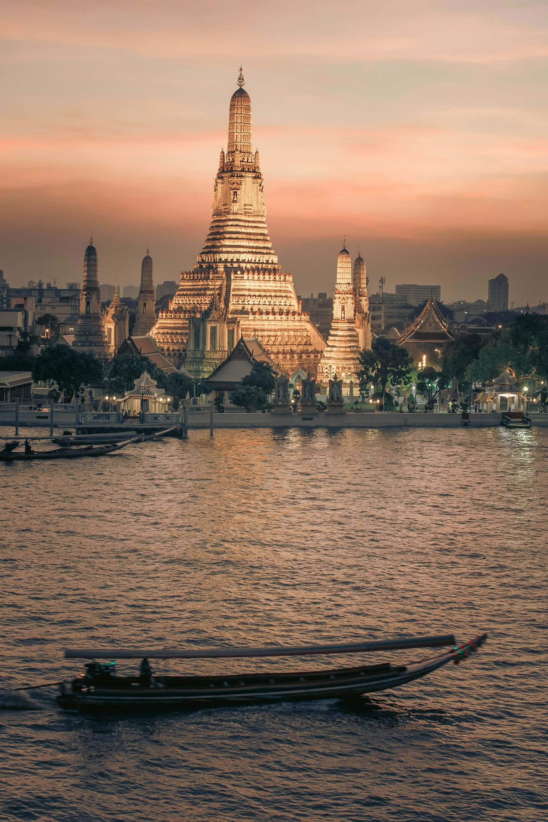 Wat Arun beside the Chao Phraya River at dusk in Thailand